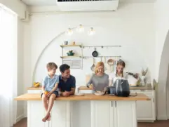 Family in kitchen with smart gas leak alarm on wall for home safety