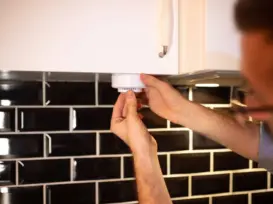 homeowner testing carbon monoxide alarm to detect gas leak in modern kitchen for home safety