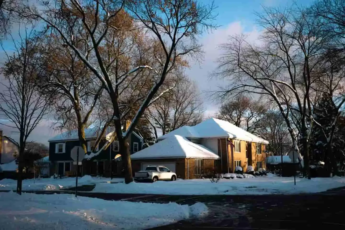 Snow-covered American home on a cold winter morning, illustrating the need for efficient heating and smart thermostats during winter