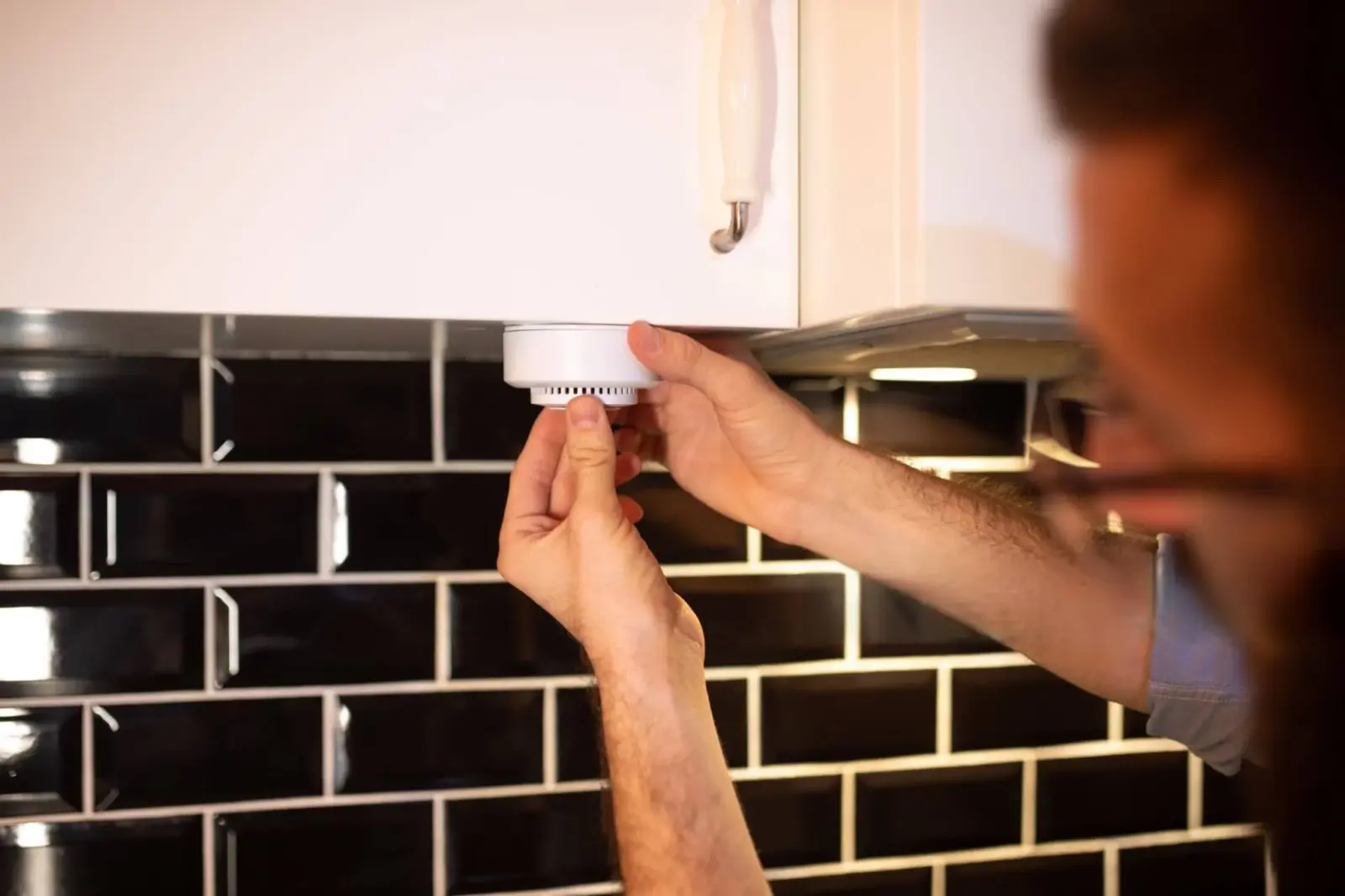 Can a Carbon Monoxide Alarm Detect Gas Leak? 1 homeowner testing carbon monoxide alarm to detect gas leak in modern kitchen for home safety