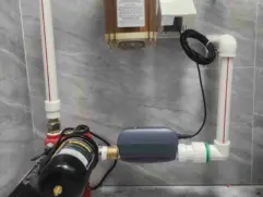 A clean, bright North American home interior showing a main water shutoff valve with a smart automatic valve installed on the pipe by insurance requirement.