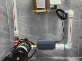 A clean, bright North American home interior showing a main water shutoff valve with a smart automatic valve installed on the pipe by insurance requirement.