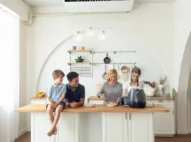 Family in kitchen with smart gas leak alarm on wall for home safety
