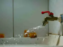 Leaking faucet spraying water — a common household leak scenario that smart water shutoff valves can automatically prevent in 2025