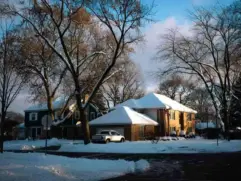 Snow-covered American home on a cold winter morning, illustrating the need for efficient heating and smart thermostats during winter