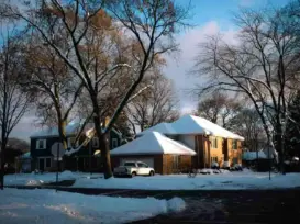 Snow-covered American home on a cold winter morning, illustrating the need for efficient heating and smart thermostats during winter